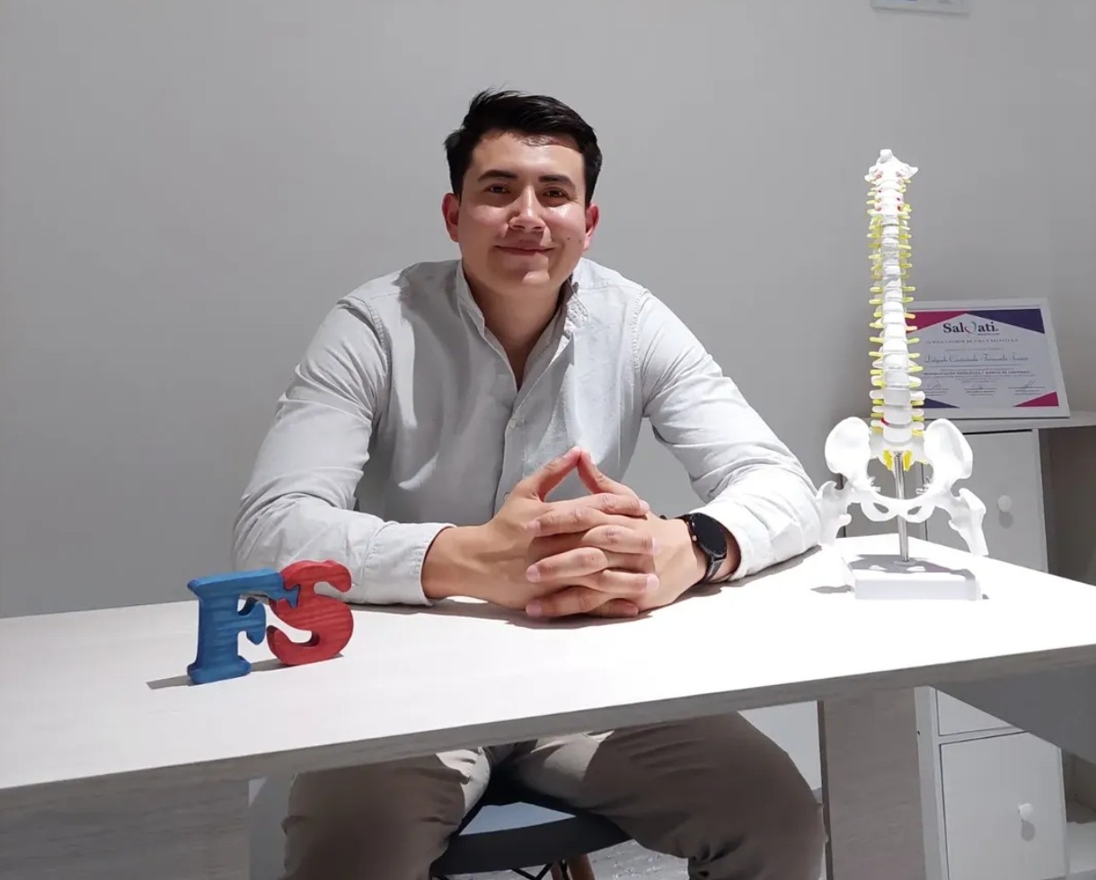 Fernando Junior Delgado Castañeda en su consultorio de fisioterapia — certificados al fondo